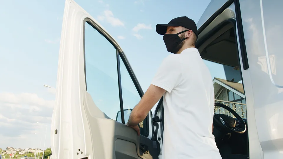 Courier standing beside the open driver door of a white cargo van